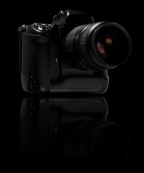 Professional digital camera over black background. With reflection.