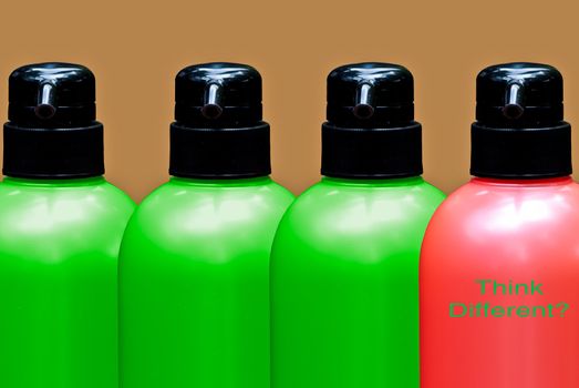 Colourful bottles put together on a brown background with one bottle different color then others with 'think different' text
