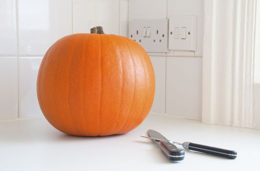 Preparing Halloween, a pumpkin and two knives in a kitchen