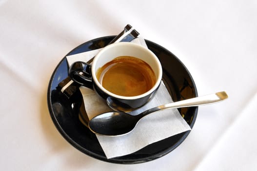 A cup of espresso on a white tablecloth