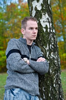 Boy is waiting befront of a tree