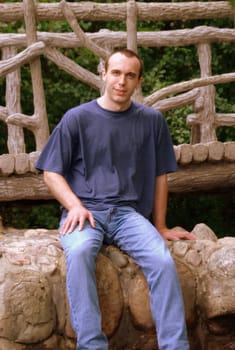 A young man sitting on a bridge.