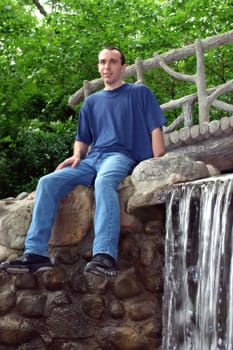 A young man sitting on a bridge.