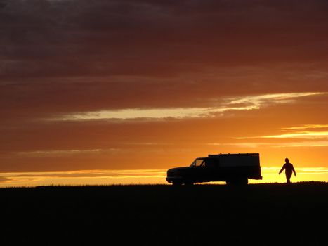 Old vehicle in silhouette at sunset in a field