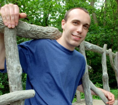 A young man sitting on a bridge.