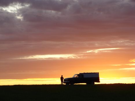 Old vehicle in silhouette at sunset in a field