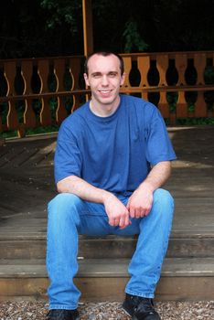 A young man sitting on a wooden step.