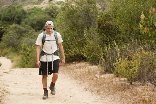 A young male walking on a mountain trail during a hiking trip.