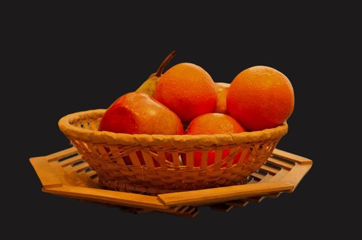The isolated basket with oranges, an apple and a pear on a dark blue background