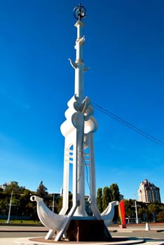 A monument in the form of a boat and a high pole. against the blue sky .