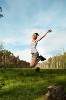 The young girl has jumped against wood and the sky