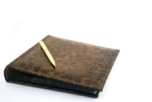 The golden pen with an album for photos on a white background