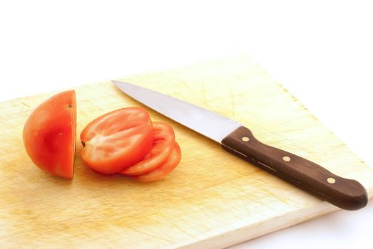 The cut tomato and knife on a board on a white background.