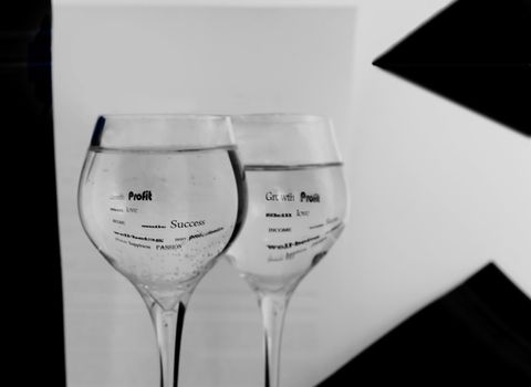 Two black-and-white glasses in water are reflected words.