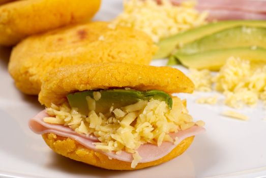 Arrangement of traditional arepas filled with avocado, ham and cheese