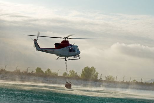 Fire brigade helicopter dipping the water container to refill