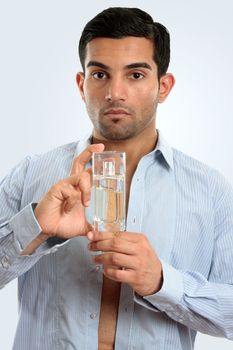 Closeup of a man getting dressed holding a blass bottle of men's cologne