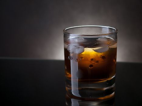 Glass of whiskey and ice, dark colors