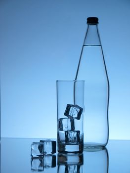 Glass water bottle and glass on blue