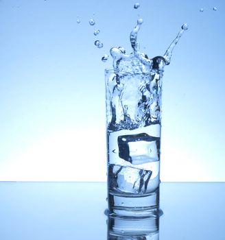 Ice cube entering a glass of water with a splash