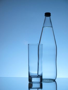 Glass in front of bottle of water ready to be filled 