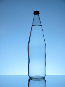 Glass water bottle on blue background