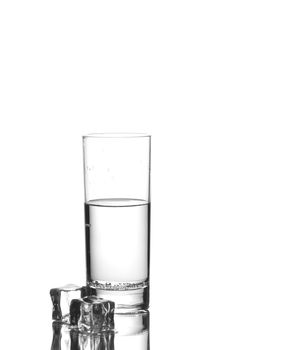 Glass of water with two ice cubes nearby