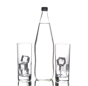 Glass bottle of water and two glasses with ice cubes, isolated 