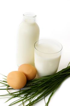 Bottle and glass of milk with eggs on white