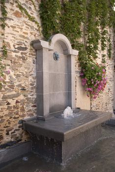 Urban fountain and flowers onext to a brickwall