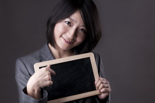 Happy woman in suit pointing to blackboard