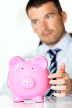 young man with pink piggy bank in office