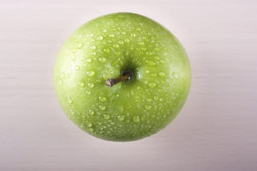Fresh granny smith apple shot from directly above on board with water drops