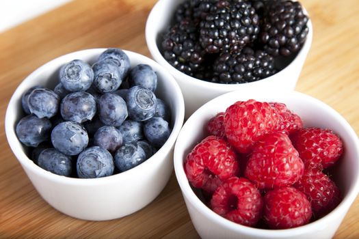 Three bowls of blueberries, blackberries and raspberries