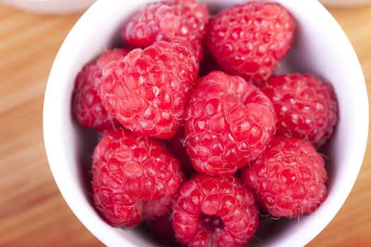 Raspberries in white bowl shot from directly above.