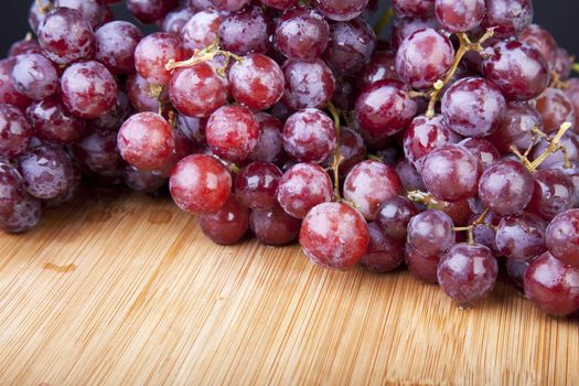 Moist red grapes on cutting board.