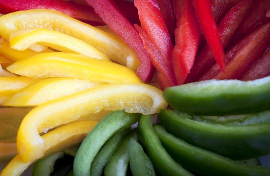 Closeup of red, yellow and green bell pepper slices.