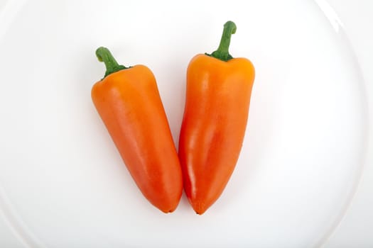 Two  sweet orange peppers in white plate.