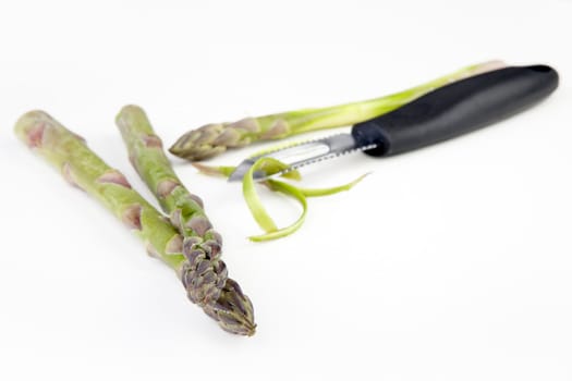 Stalks of asparagus with vegetable peeler.  Shallow depth of field.