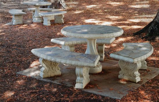 Concrete and stone Round Picnic tables in a wooded grove