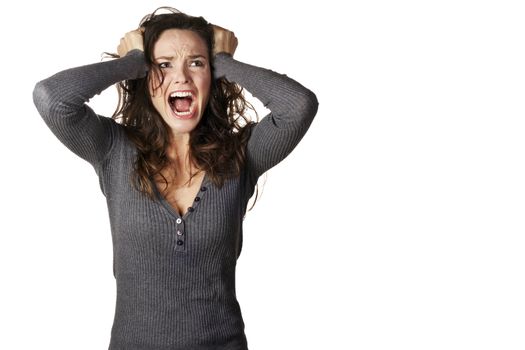 A frustrated and angry woman is screaming out loud and pulling her hair.