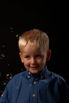 Blond boy getting soap bubbles blown in his face