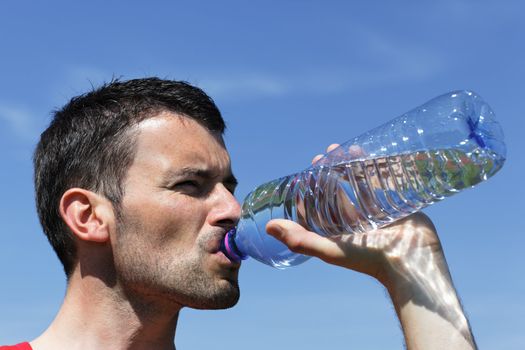 young man drinking water in blue sky
