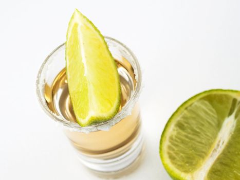 Shot of tequila with a halved lime and slice of lime