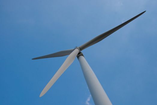 Wind mill power generator against blue clear sky.