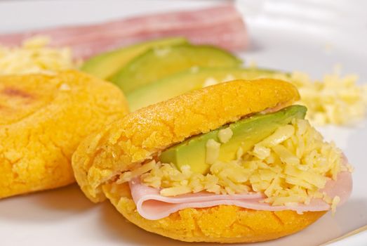 Golden arepas filled with ham, cheese and avocado