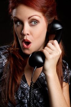 Shocked woman using vintage telephone