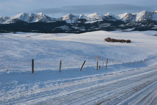 The Bridger Mountain Range, country road and snow draped range land on a Winter morning, Gallatin County, Montana, USA