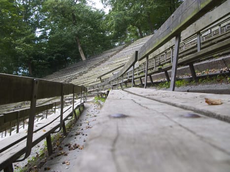 Empty wooden tribune without any audience covered with leafs