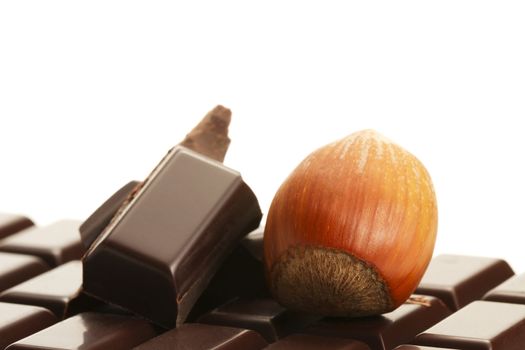 hazelnut and plain chocolate pieces on a plain chocolate bar on white background